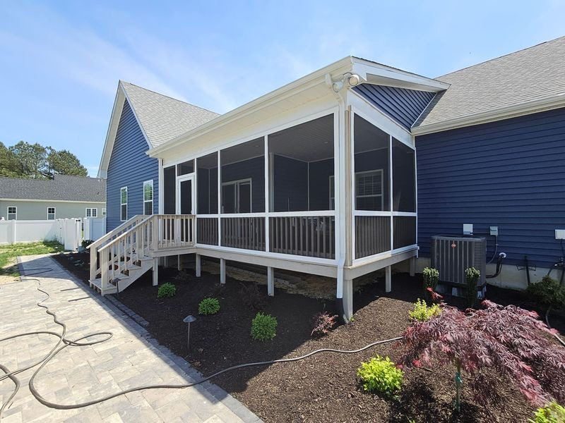 A newly built screened-in porch attached to a blue house.