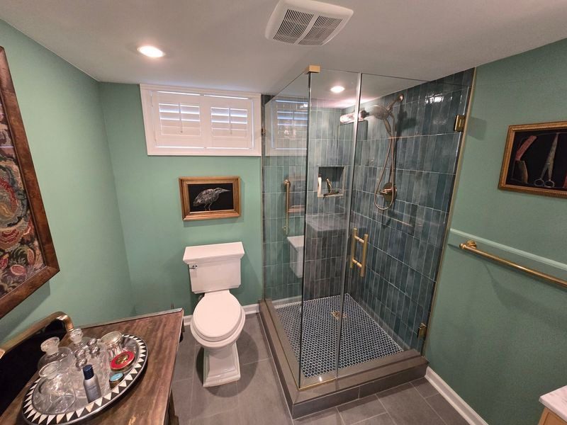 Compact bathroom with glass shower and wall-mounted toilet.