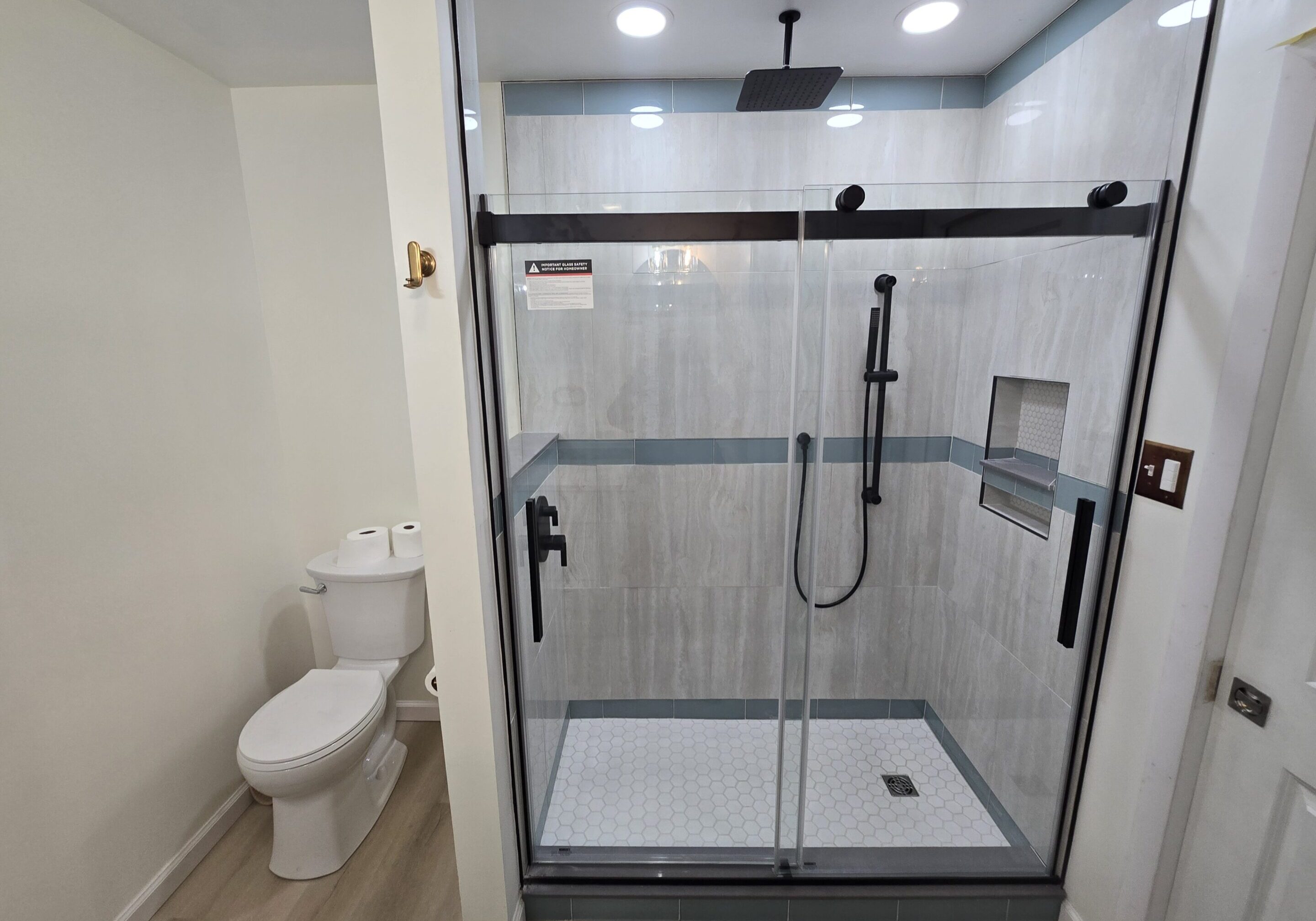 Modern bathroom with glass-enclosed dual shower and toilet.
